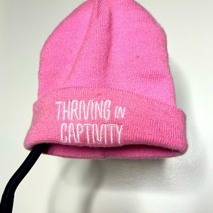 ‘Thriving in captivity’ pink beanie